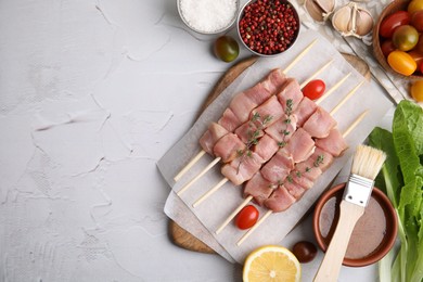 Photo of Flat lay composition of skewers with cut raw meat, thyme, tomatoes and marinade on light textured table. Space for text