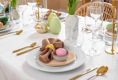 Festive Easter table setting with painted eggs, burning candles and yellow tulips