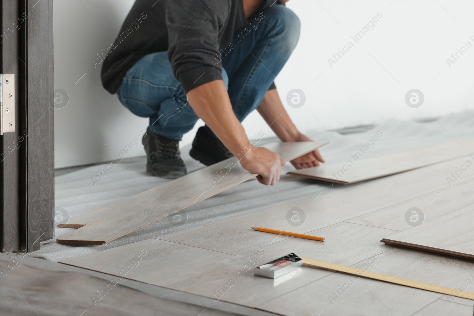 Photo of Worker installing new laminate flooring in room, closeup