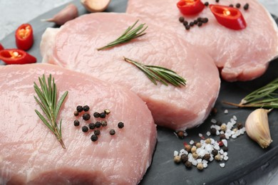 Photo of Pieces of raw pork meat, chili pepper and spices on board, closeup