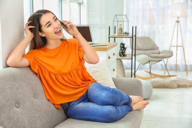 Photo of Attractive young woman talking on mobile phone at home