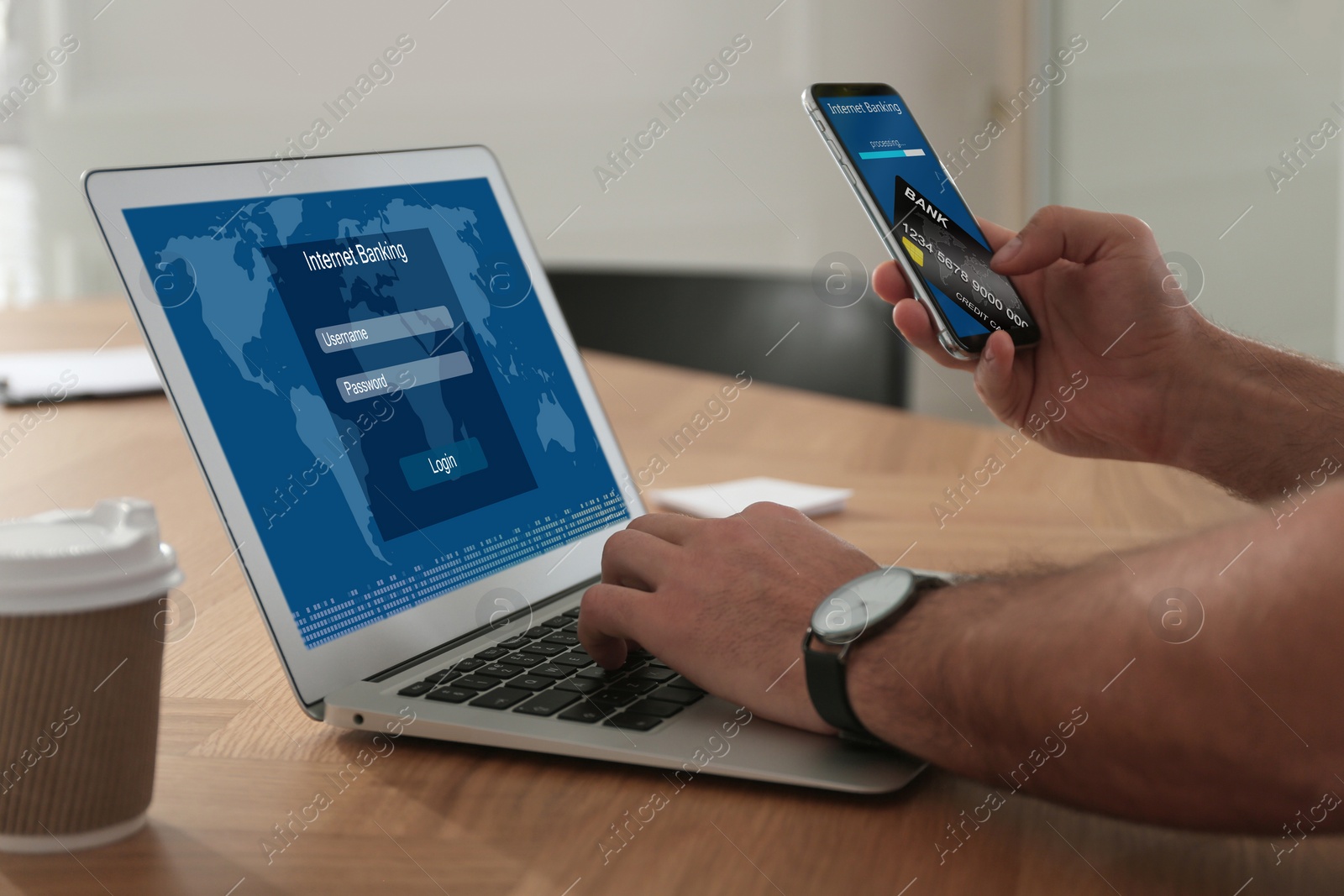 Image of Man using online banking application on laptop and smartphone at wooden table, closeup