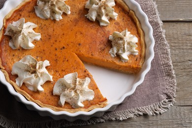 Delicious pumpkin pie with whipped cream on wooden table, above view