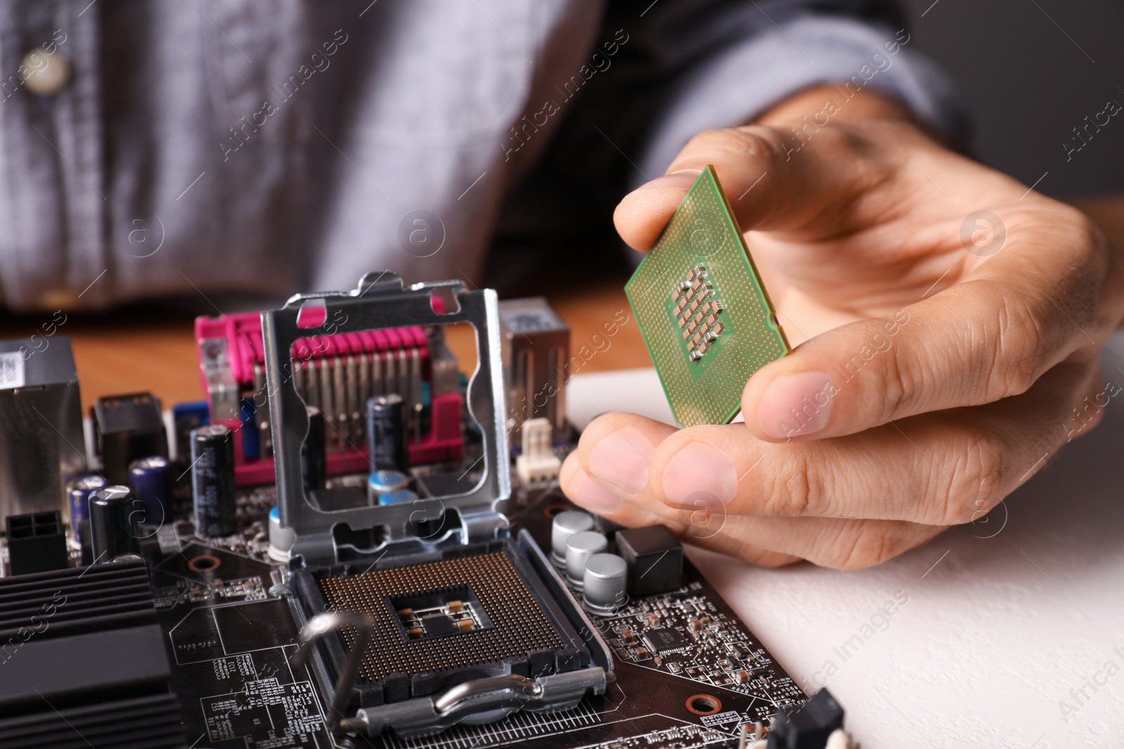 Photo of Technician repairing computer motherboard at table, closeup. Electronic device