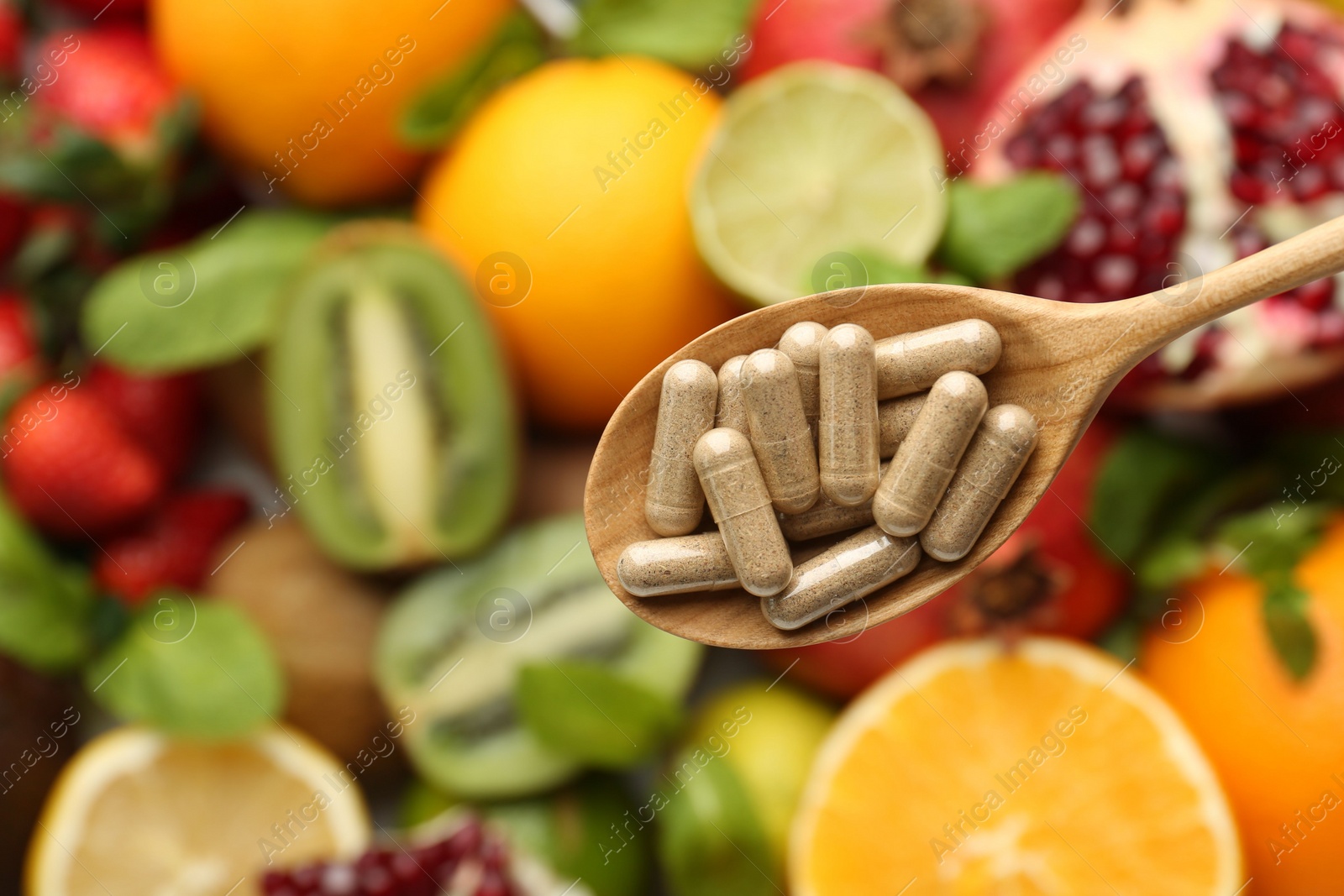 Photo of Vitamin pills in spoon over fresh fruits, top view. Space for text