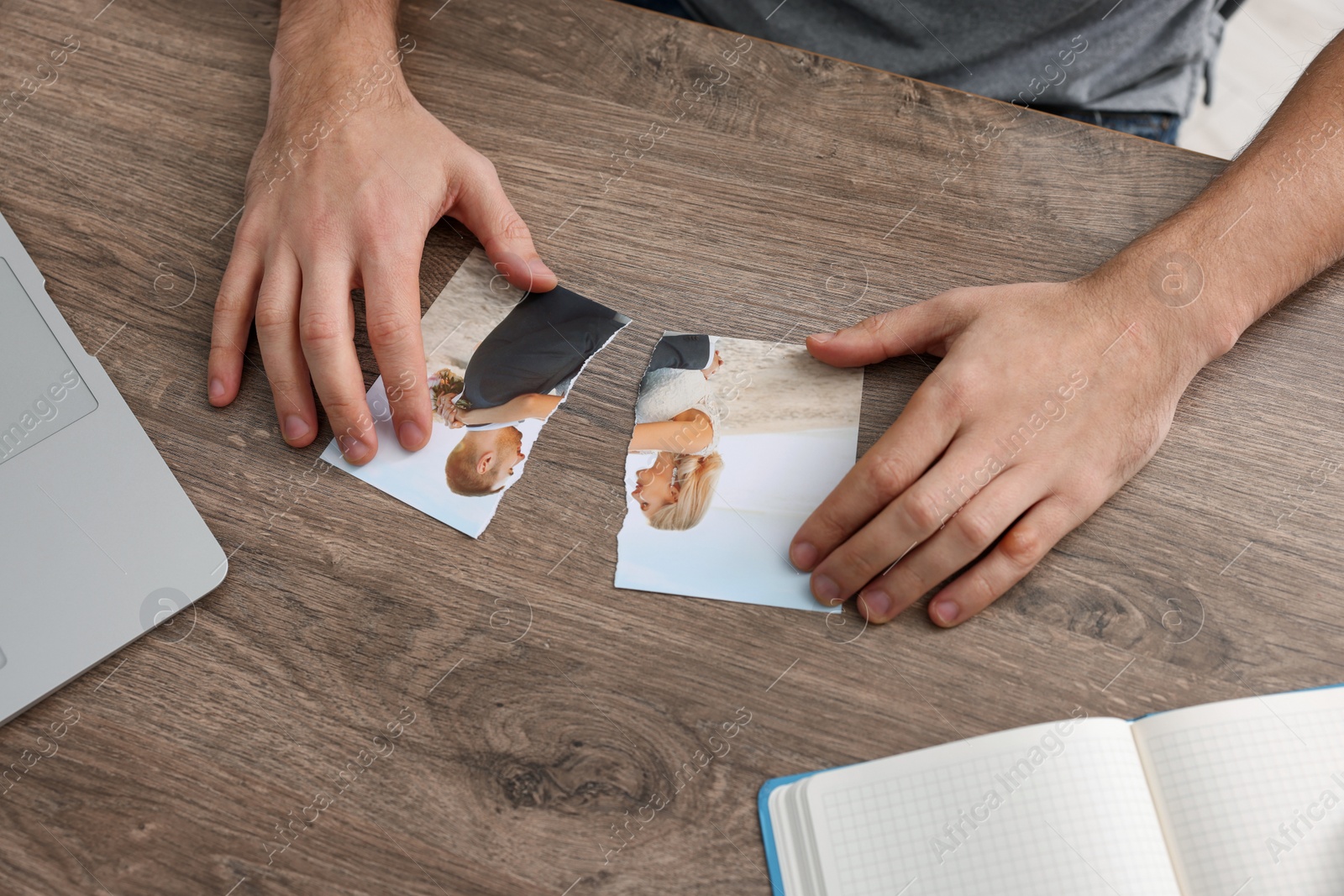 Photo of Man with parts of photo at table indoors, closeup. Divorce concept