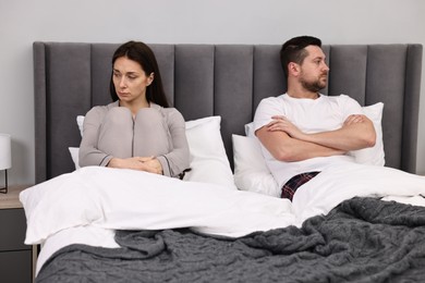 Photo of Offended couple ignoring each other after quarrel in bed. Relationship problems