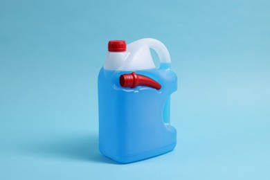 Photo of Plastic canister with color liquid on light blue background