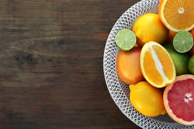 Photo of Bowl with different citrus fruits on wooden table, top view. Space for text