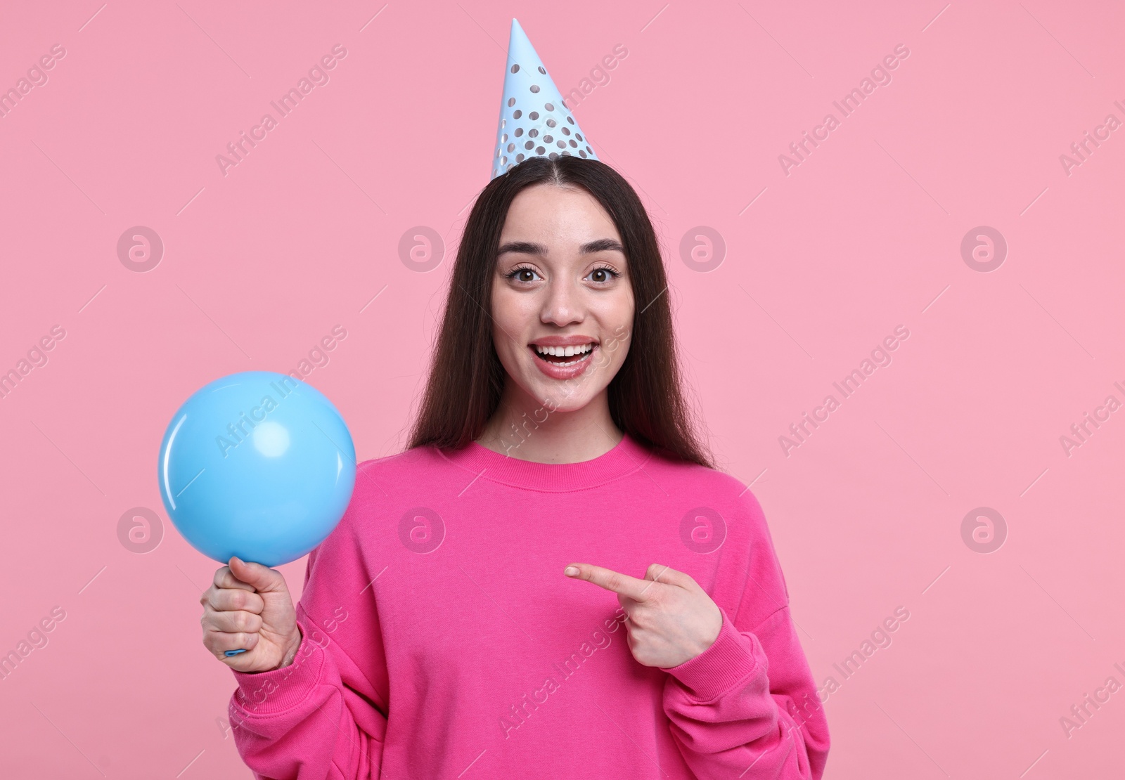 Photo of Happy woman in party hat with balloon on pink background