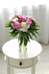 Photo of Vase with bouquet of beautiful peonies on table in room