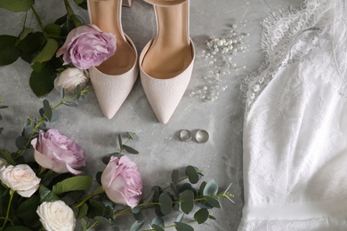 Photo of Flat lay composition with white wedding dress and shoes on grey marble table