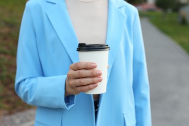 Coffee to go. Woman with paper cup of drink outdoors, closeup