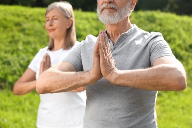 Photo of Senior couple practicing yoga outdoors, selective focus