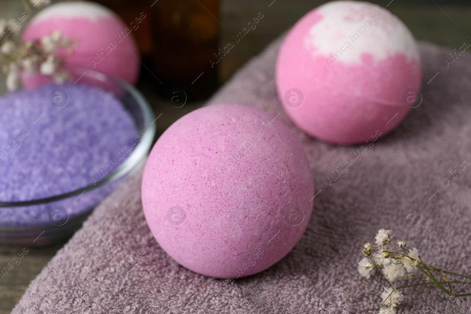 Photo of Beautiful aromatic bath bombs and gypsophila flowers on soft towel, closeup