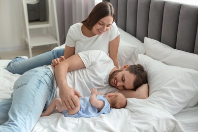 Photo of Happy family. Parents with their cute baby on bed indoors