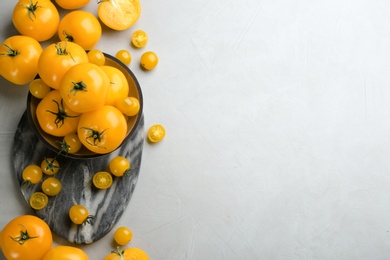 Photo of Ripe yellow tomatoes on grey table, flat lay. Space for text