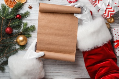 Santa Claus holding scroll and Christmas decor on wooden background, top view