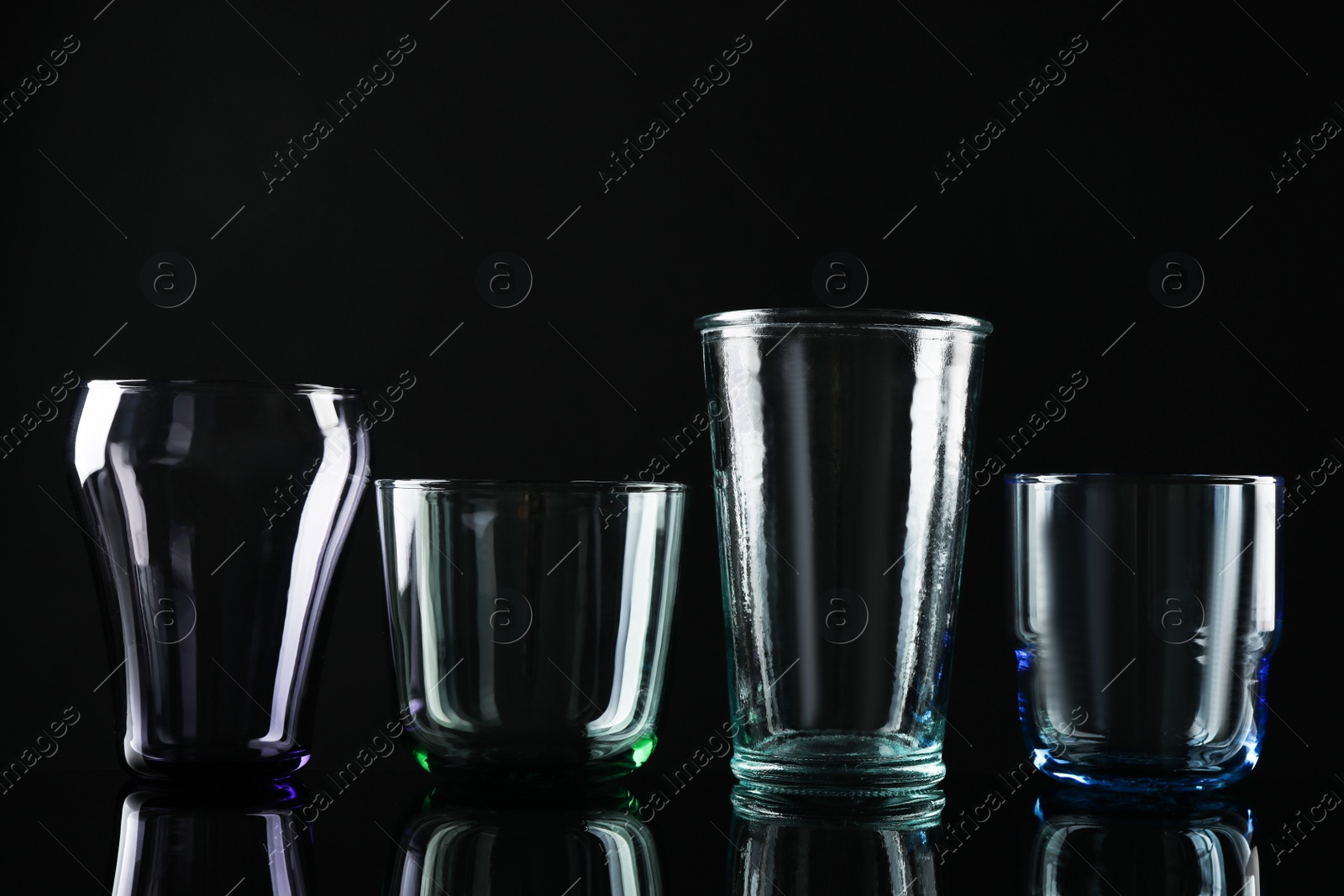 Photo of Set of different colorful empty glasses on black background