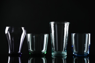 Set of different colorful empty glasses on black background