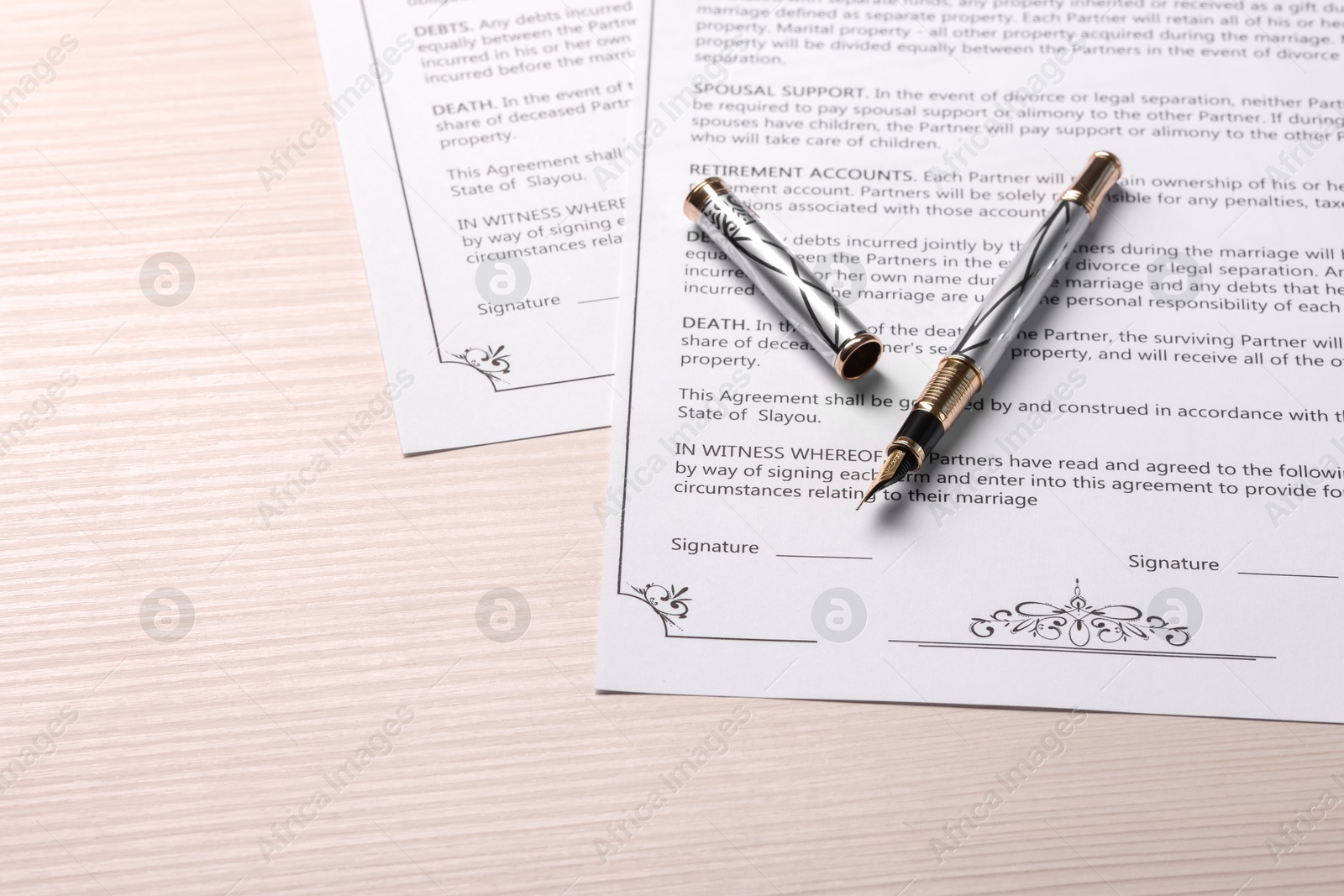 Photo of Marriage contracts and pen on light wooden table, space for text