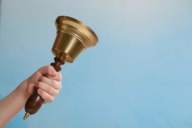 Photo of Pupil with school bell on light blue background, closeup. Space for text