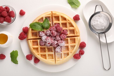 Photo of Tasty Belgian waffle with fresh raspberries, honey and powdered sugar on white table, flat lay