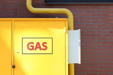 Photo of Gas distribution system with pipe near red brick wall outdoors, space for text