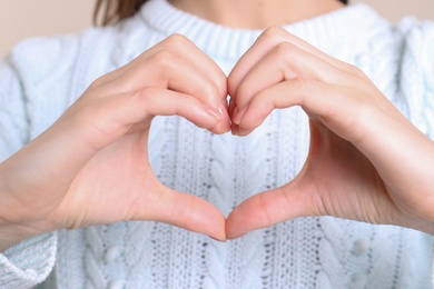 Photo of Young woman making heart with her hands, closeup