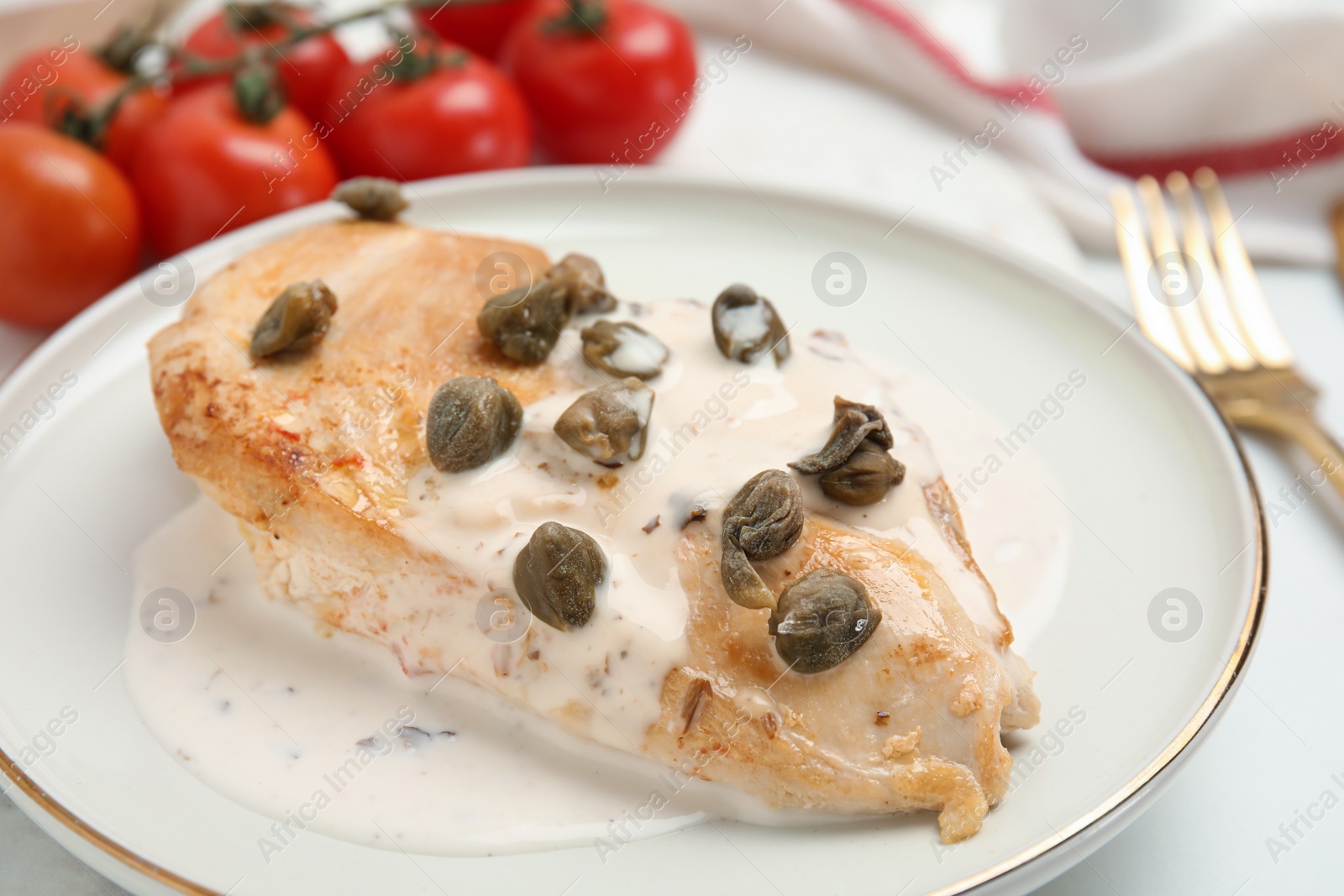 Photo of Delicious chicken fillet with capers and sauce served on white table, closeup