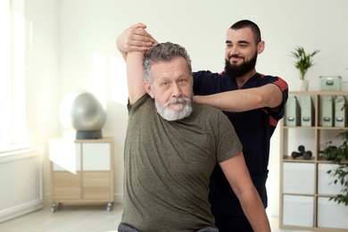 Photo of Physiotherapist working with patient in clinic. Rehabilitation therapy