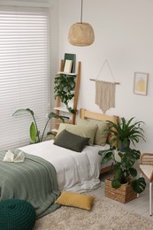 Photo of Large comfortable bed and potted houseplants in stylish bedroom. Interior design