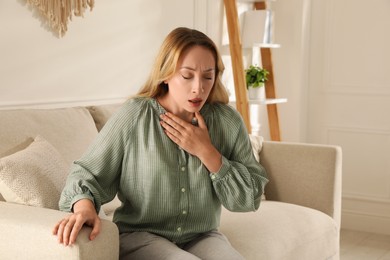 Photo of Young woman suffering from pain during breathing at home