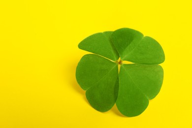 Photo of Beautiful green four leaf clover on yellow background, closeup. Space for text