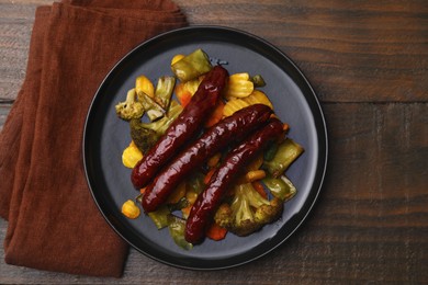 Photo of Delicious smoked sausages and baked vegetables on wooden table, top view