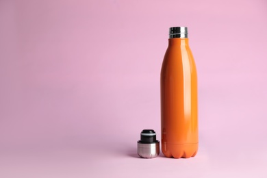 Photo of Stylish thermo bottle on pink background, space for text