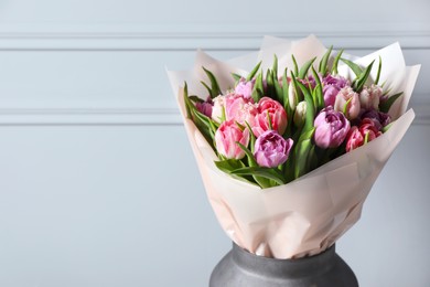Photo of Vase with bouquet of beautiful tulips near grey wall, closeup. Space for text