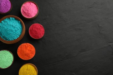 Photo of Colorful powder dyes on black background, flat lay with space for text. Holi festival