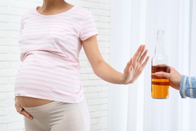 Photo of Pregnant woman declining whiskey indoors. Alcohol harm