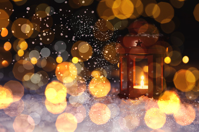 Image of Lantern with burning candle on snow outdoors, bokeh effect