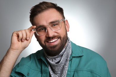 Photo of Fashionable young man in stylish outfit with bandana on grey background
