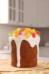 Photo of Delicious Easter cake decorated with pieces of candied fruits on white table in kitchen