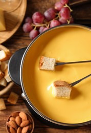 Pot of tasty cheese fondue and snacks on table, flat lay