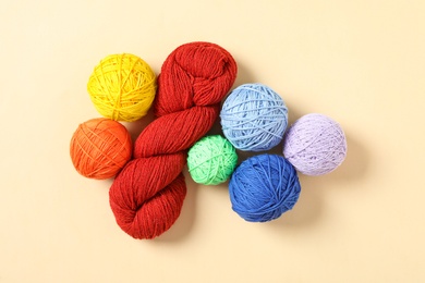 Photo of Colorful woolen yarns on beige background, flat lay