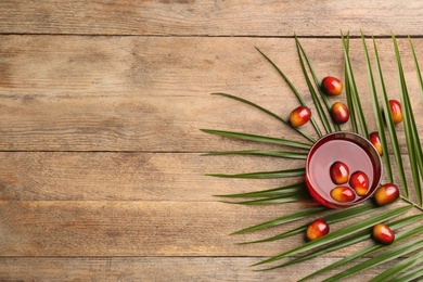 Image of Palm oil in glass with fruits and tropical leaf on wooden table, flat lay. Space for text