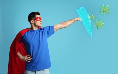 Image of Man wearing superhero costume fighting against viruses on light blue background