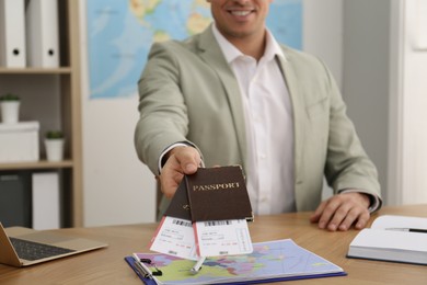 Photo of Travel agent with tickets and passports at table in office, closeup