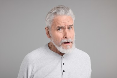 Photo of Portrait of surprised senior man on grey background