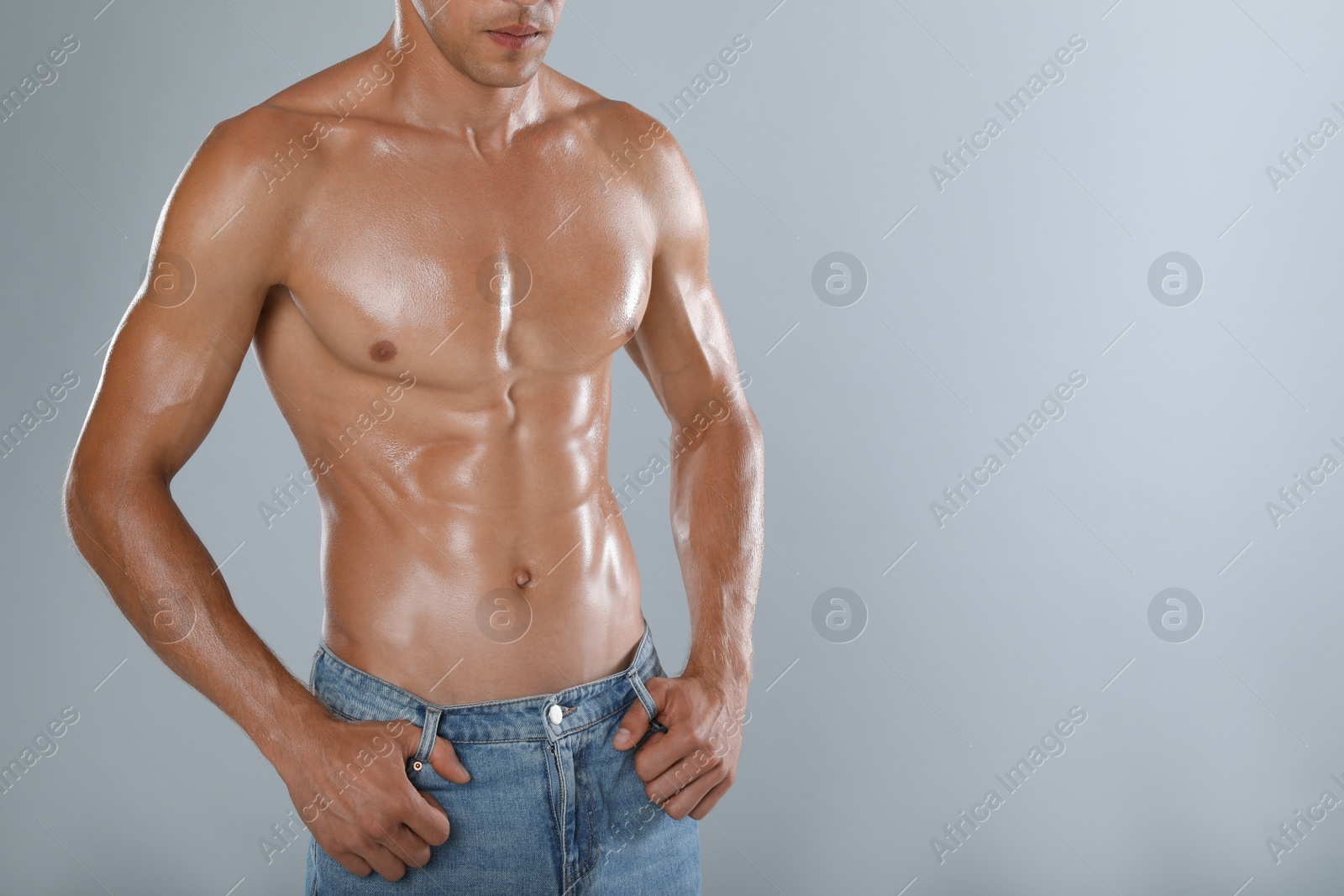 Photo of Shirtless man with slim body on grey background, closeup. Space for text