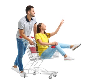 Young couple with shopping cart on white background